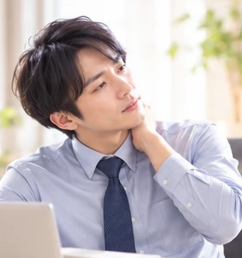 首に手を当てるワイシャツ姿の男性